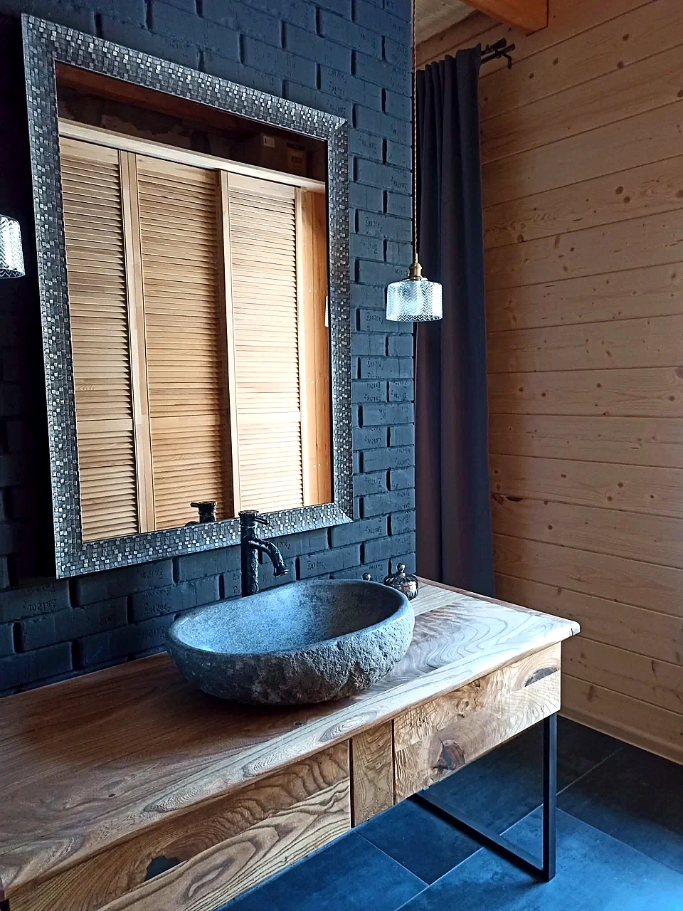 Rustic river stone bathroom sink on a wooden vanity with gray marble-look wall tiles
