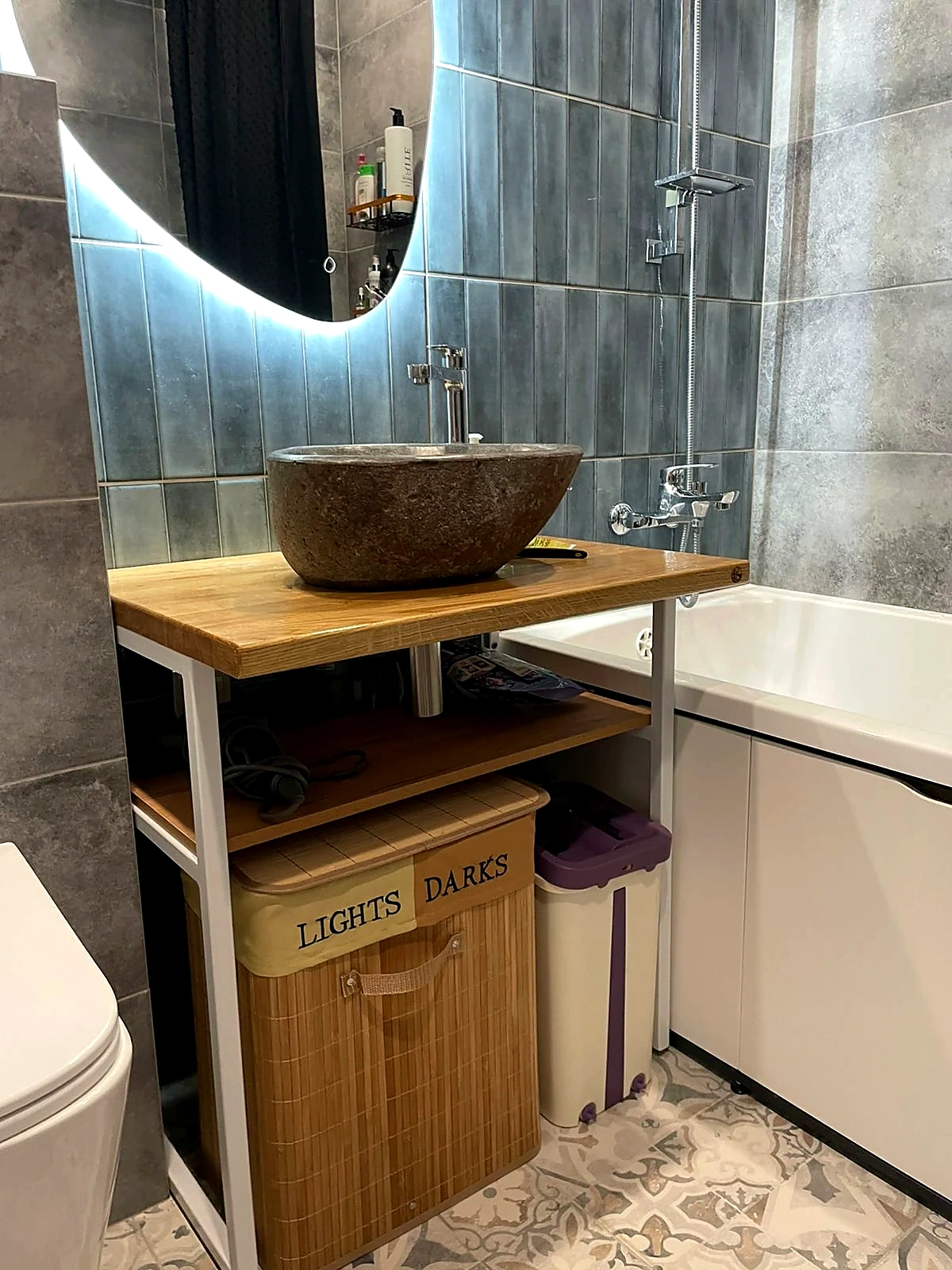 Natural stone vessel sink on a solid wood countertop beside a bathtub in a modern bathroom