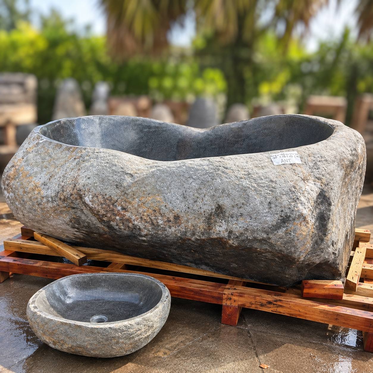 Large handcrafted natural stone bathtub with a smaller stone vessel sink for size comparison